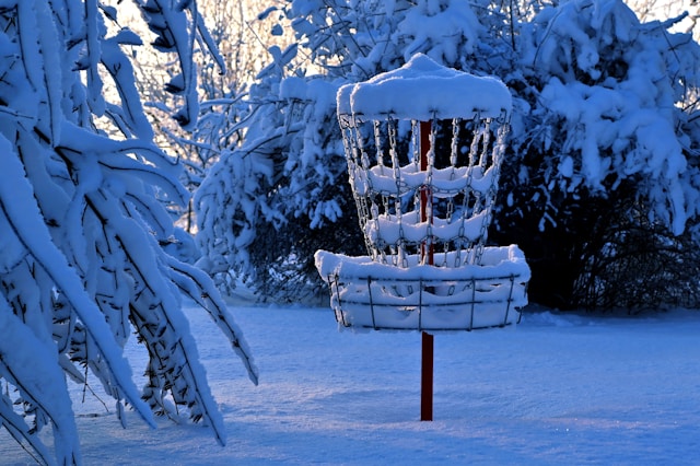 A disc golf basket in the snow.