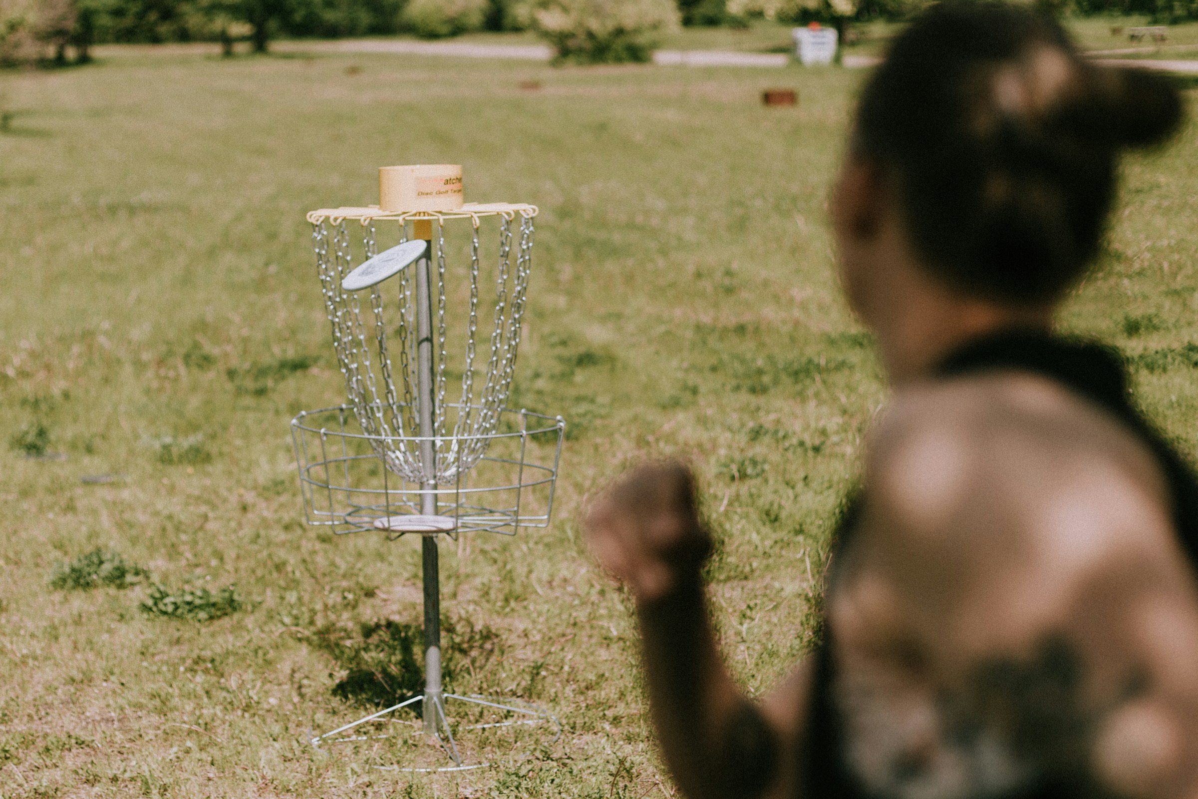 An over the shoulder shot of a disc being thrown into a disc golf basket